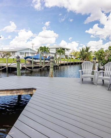 Screened-in pool with spa overlooking canal and waterfront homes under blue sky